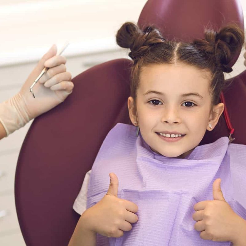 girl at the orthodontist gives two thumbs up